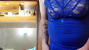 Crossdressing snygging i en blå klänning retar med sina bröst och kuk